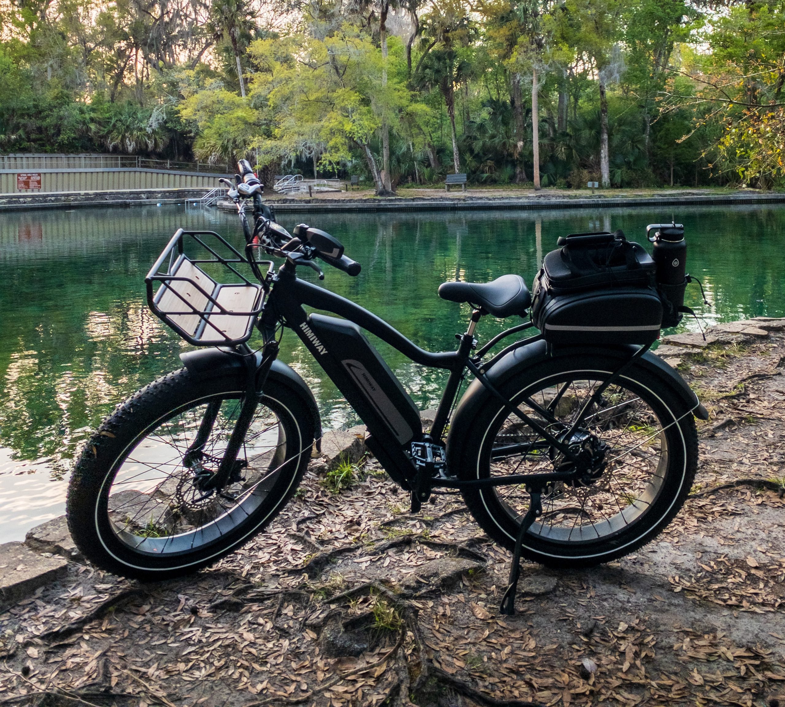 electric bike with front and rear accessory racks parked by a lake