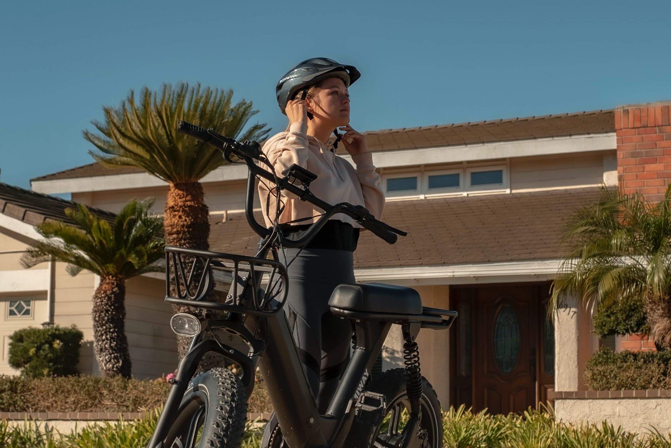 girl putting on her helmet before getting on her electric bike