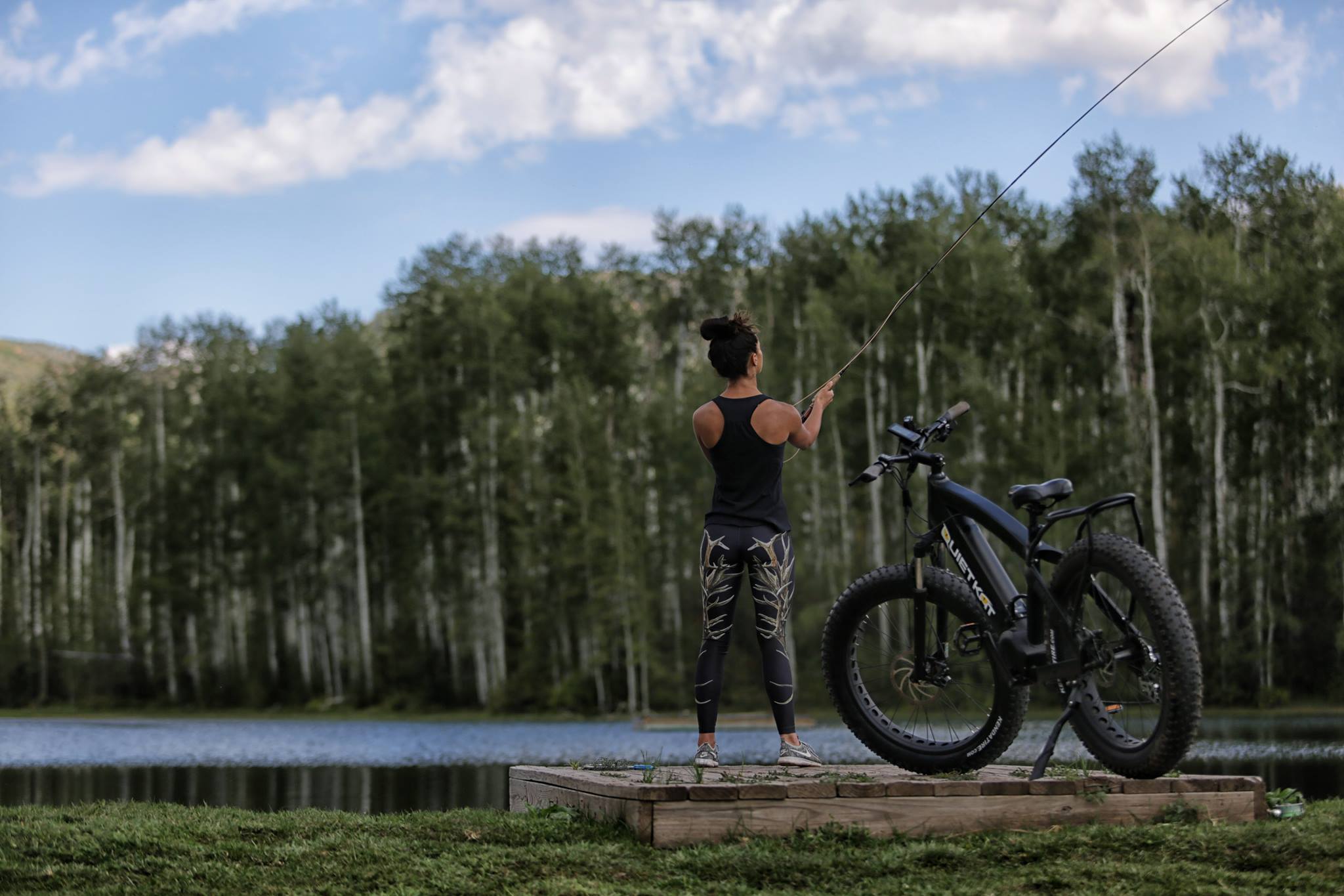 girl fishing off a dock with her electric bike parked beside her