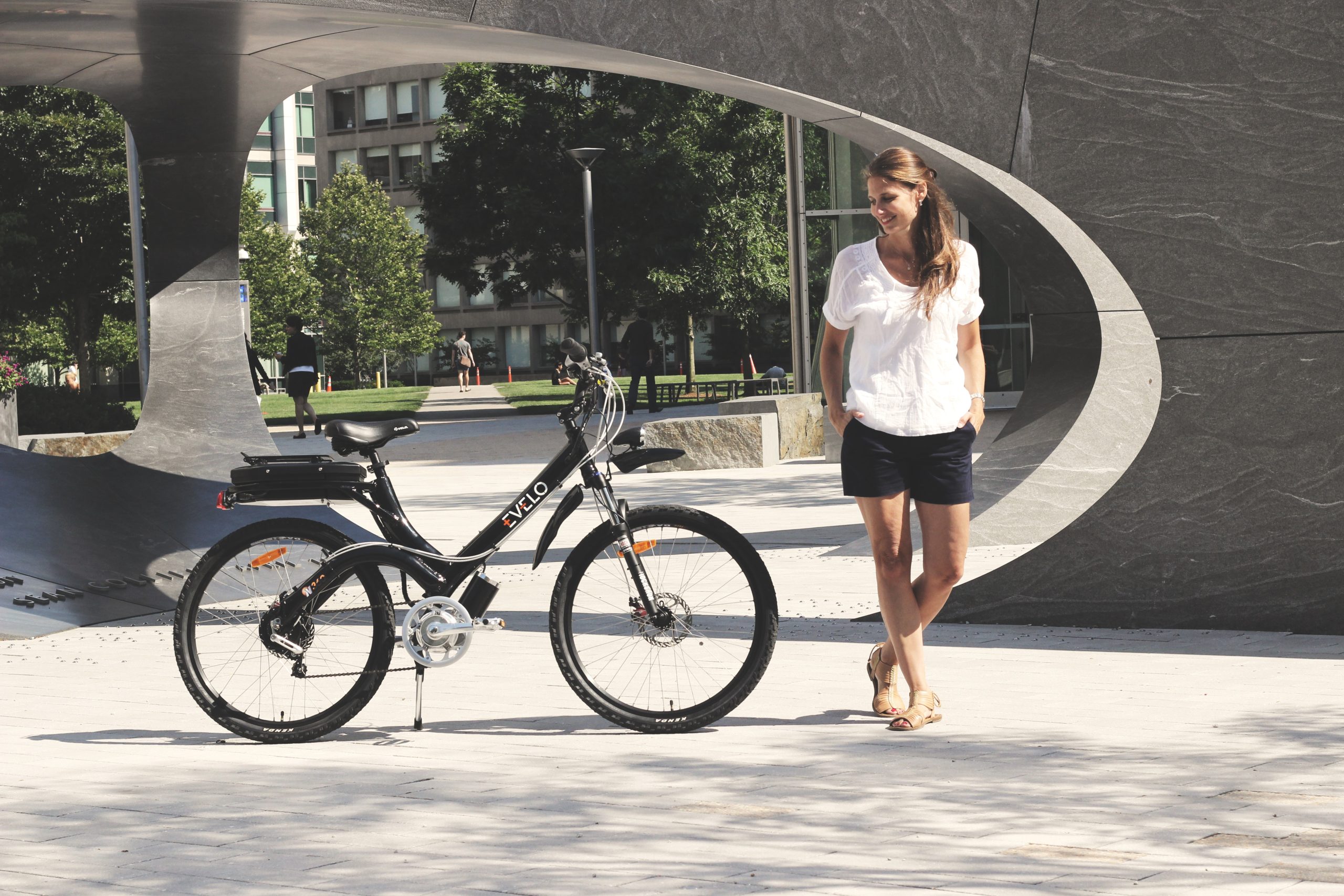 girl standing beside her black electric bike